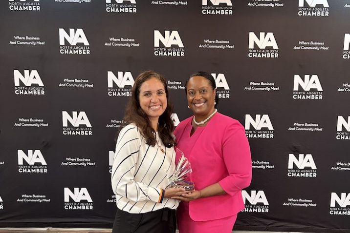 Two women pose for a picture holding an award
