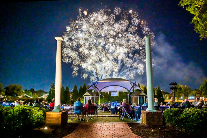Fireworks over a large crowd of people gathered in an amphitheater.